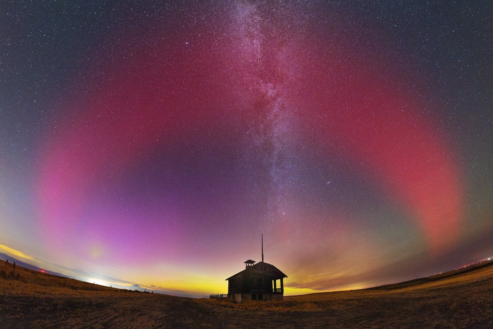 Auroral arc and milky way over schoolhouse
